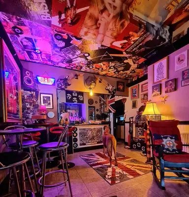 a bar with purple lights and a woman sitting at a bar at The Mercury in Blackpool