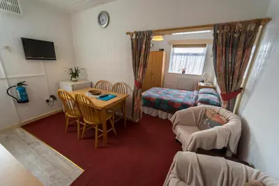 a small room with a table and a bedroom at Lyndale Holiday Flats in Blackpool