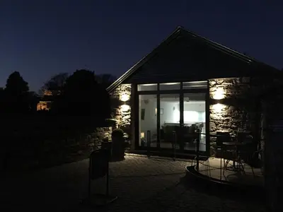 a stone house with a living room at night at The Old Roller Shed in Cartmel