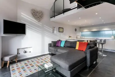 a living room with a couch and a kitchen at The Old Roller Shed in Cartmel