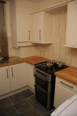 a kitchen with a stove and white cabinets at Sheil Suites in Liverpool
