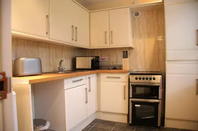 a kitchen with white cabinets and a stove top oven at Sheil Suites in Liverpool