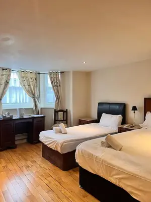 a bedroom with two beds and a desk and a window at Sheil Suites in Liverpool