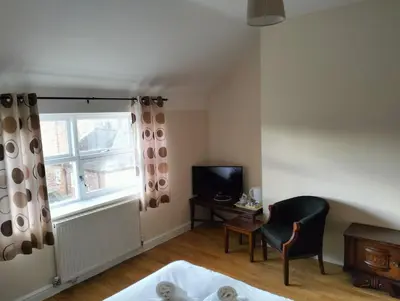 a bedroom with a bed and a chair and a television at Sheil Suites in Liverpool