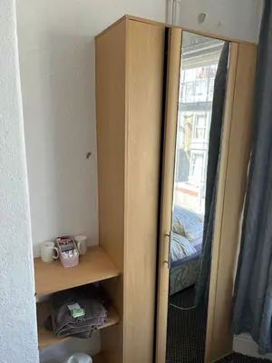 a wooden cabinet with a mirror in a room at MyRoomz Golden Strand Hotel in Blackpool