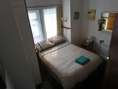 a small bedroom with a bed with a window at MyRoomz Golden Strand Hotel in Blackpool