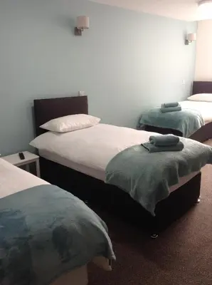 a bedroom with two beds with green pillows on them at The Bear On The Square in Millom