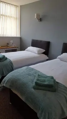 a bedroom with two beds with a green blanket on them at The Bear On The Square in Millom
