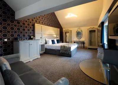 a hotel room with a bed and a couch at Stanley House Hotel & Spa in Blackburn