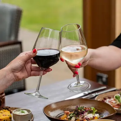 two people holding glasses of white and red wine at Stanley House Hotel & Spa in Blackburn