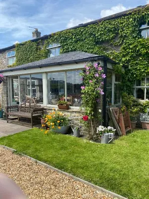 a house with a garden with a bench and flowers at Chapel Cottage Clitheroe Road in Waddington