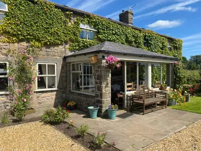 a cottage with a conservatory and a patio at Chapel Cottage Clitheroe Road in Waddington