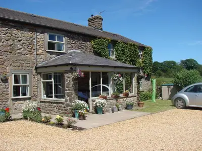a stone house with flowers in the front of it at Chapel Cottage Clitheroe Road in Waddington