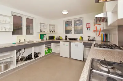 a large kitchen with white cabinets and counters at YHA Liverpool Albert Dock in Liverpool