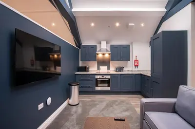 a large kitchen with blue cabinets and a couch at The Castle Collection 14 Cook Street in Liverpool