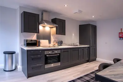 a kitchen with black cabinets and white counter tops at The Castle Collection 14 Cook Street in Liverpool