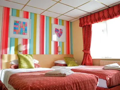 two beds in a room with colorful walls and windows at Oak Lea Hotel in Blackpool