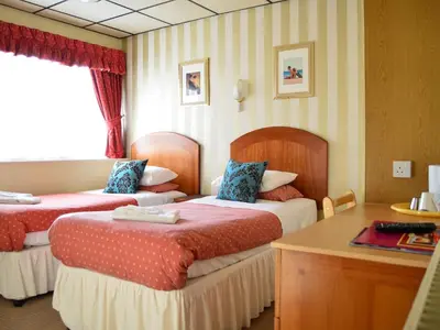 a hotel room with two beds and a desk at Oak Lea Hotel in Blackpool