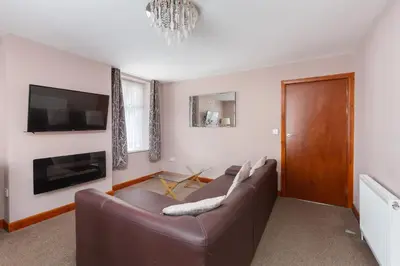 a living room with a brown couch and a tv at Beachcliffe Lodge Apartments in Blackpool