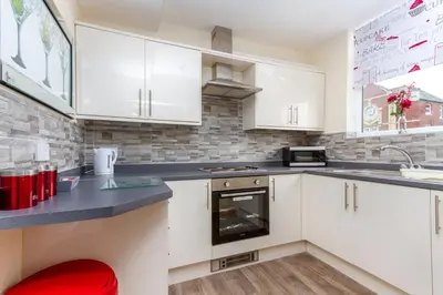 a kitchen with white cabinets and a red stool at Beachcliffe Lodge Apartments in Blackpool