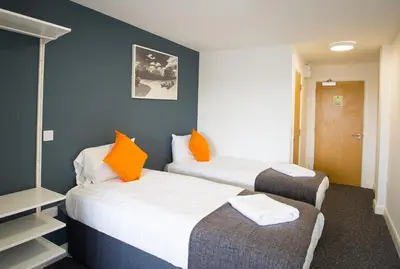 two beds with orange pillows in a room at Fox Street Apartments in Liverpool