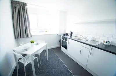 a kitchen with a white table and a white table and chairs at Fox Street Apartments in Liverpool