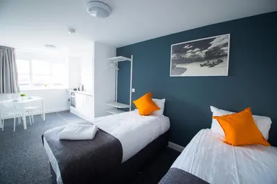 a bedroom with two beds with orange pillows and a table at Fox Street Apartments in Liverpool
