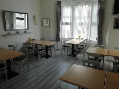 a restaurant with wooden tables and chairs and windows at The Shining Diamond in Blackpool