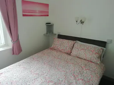 a bedroom with a bed with pink sheets and a window at The Shining Diamond in Blackpool