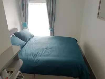 a bed with a blue comforter and a window at The Shining Diamond in Blackpool
