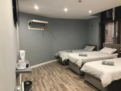 a room with three beds and a window and a room with two beds at Brownlows Inn in Liverpool