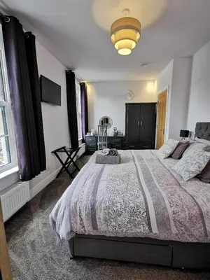 a bedroom with a large bed and a lamp at Saracens House in Preesall