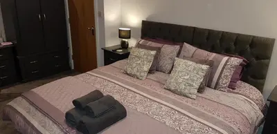 a bedroom with a large bed with pink and gray pillows at Saracens House in Preesall