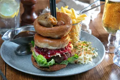 a plate with a sandwich with onion rings and fries at The Bold Hotel; BW Signature Collection in Southport