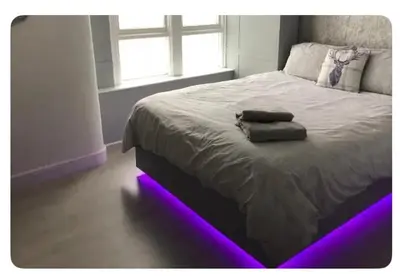 a bedroom with a bed with purple lights on it at The Elk in Blackpool