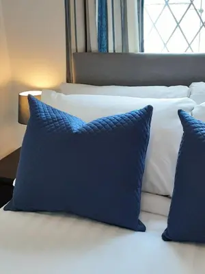 a bed with two blue pillows on it at The Cardoun in Blackpool