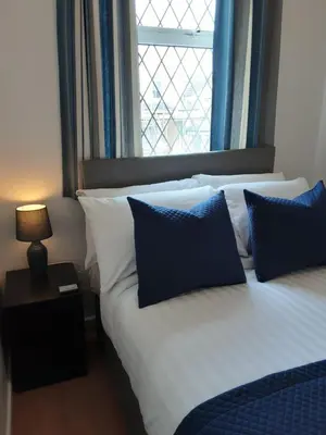 a bedroom with two beds with blue pillows and a window at The Cardoun in Blackpool