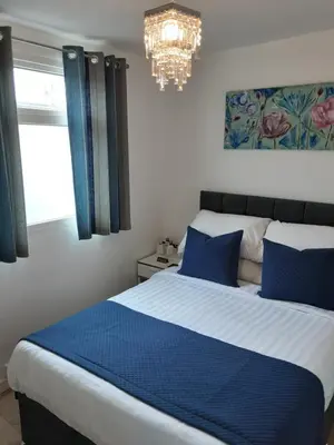 a bedroom with a blue and white bed and a chandelier at The Cardoun in Blackpool