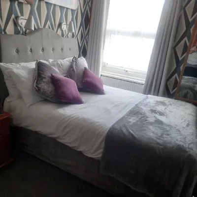a bed with purple pillows on it with a window at Tracey's Driftwood in Blackpool