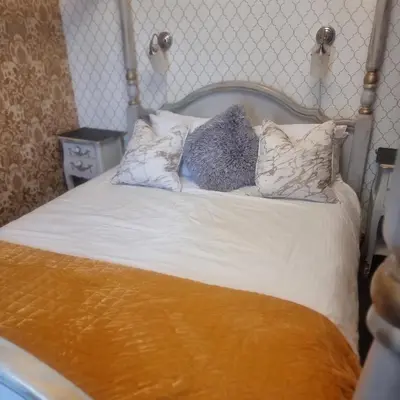a bed with white sheets and pillows on it at Tracey's Driftwood in Blackpool