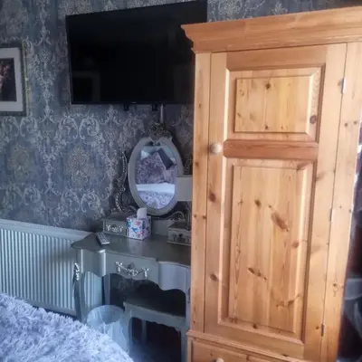 a bedroom with a wooden cabinet and a mirror at Tracey's Driftwood in Blackpool