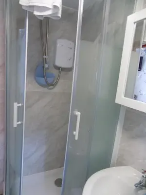 a bathroom with a glass shower door next to a toilet at Tracey's Driftwood in Blackpool