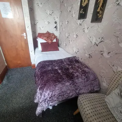 a small bedroom with a bed with a purple blanket at Tracey's Driftwood in Blackpool
