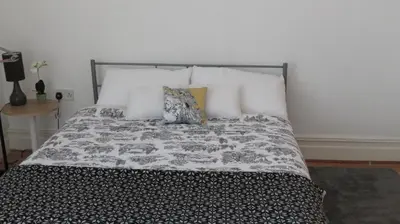 a bed with a black and white blanket and pillows at Beach house in Crosby
