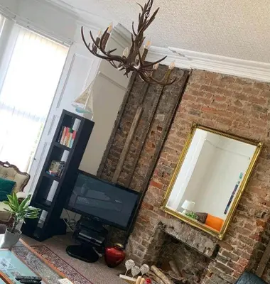 a living room with a fireplace with a mirror and a television at Beach house in Crosby