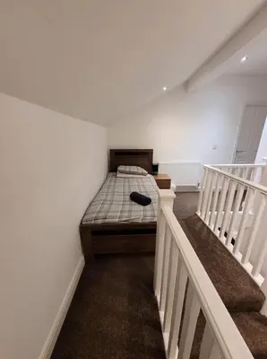 a bedroom with a bed in a room with stairs at 3 Laurel Court in Ulverston