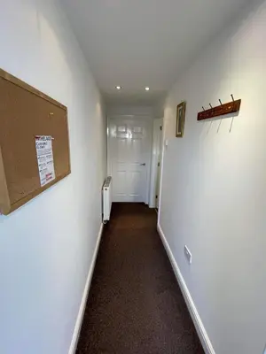 a hallway with a white wall and a white door at 4 Laurel Court in Ulverston