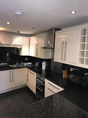 a kitchen with white cabinets and black counter tops at 4 Laurel Court in Ulverston