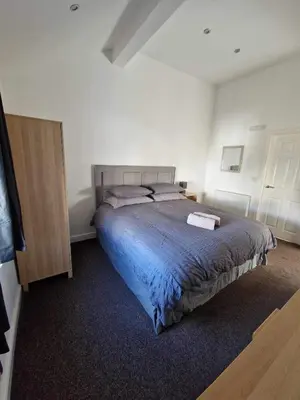 a bedroom with a large bed with a blue blanket at 5 Laurel Court in Ulverston