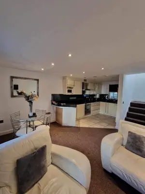 a living room with two couches and a kitchen at 5 Laurel Court in Ulverston